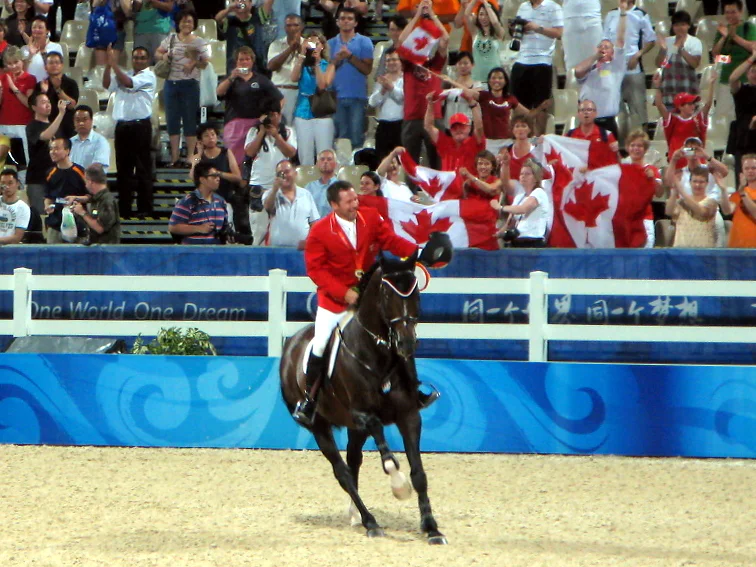 Eric Lamaze riding the dark bay stallion Hickstead past cheering Canadian supporters at the 2008 Olympic Games.